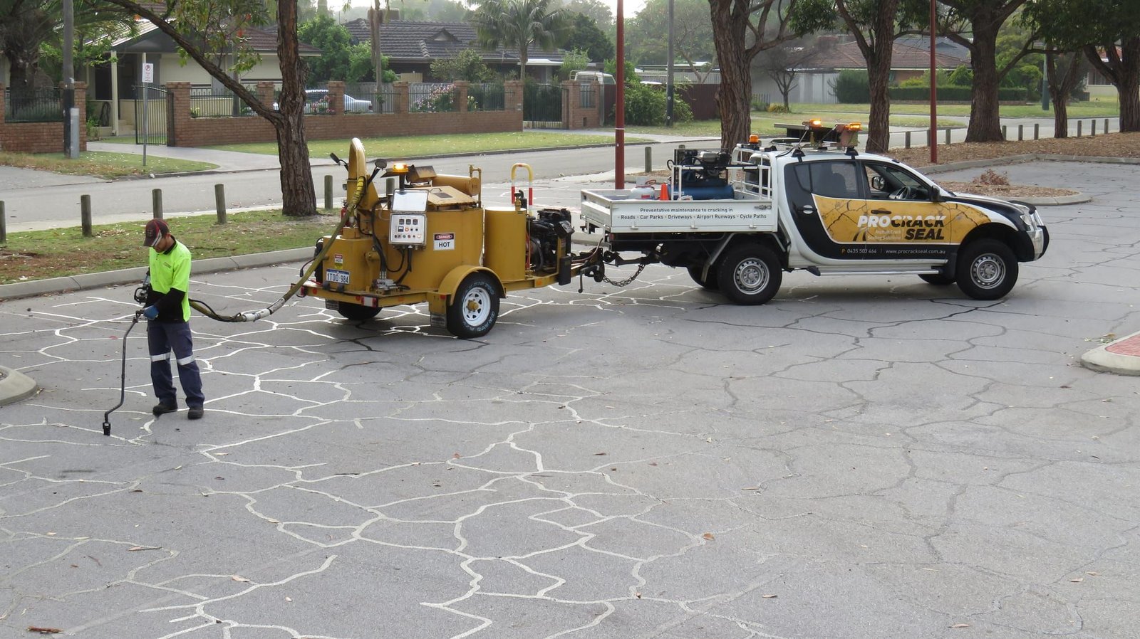 Pro Crack Seal crew applying hot pour crack sealing beside a branded support vehicle